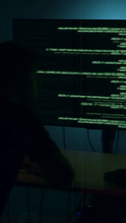 Hacker engaged in cyber attack, focused on multiple screens displaying code and Stock Footage 323743435