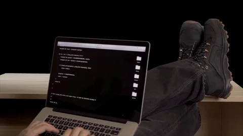 Hacker feet up to table. Hacker with laptop coding exploit to crack code. Man in Video stock 82888667