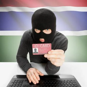 Hacker with flag on background holding ID card in hand - Gambia Hacker wit... 写真素材