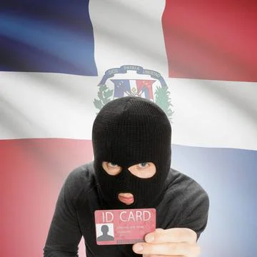 Hacker with flag on background holding ID card in hand - Dominican Republi... Stock Photos