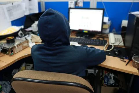 A hacker in front of a computer is doing his job Stock Photos