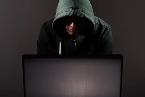 Hacker in front of his computer. Dark face Stock Photos