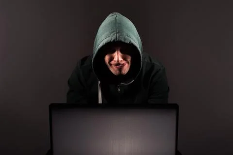 Hacker in front of his computer. Dark face Stock Photos