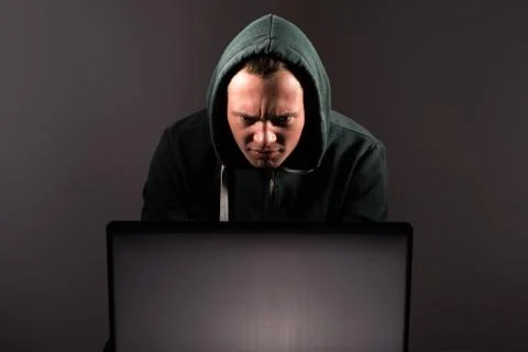 Hacker in front of his computer. Dark face Stock Photos