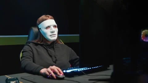 The hacker girl at the computer removes the mask from her face and looks at the 動画素材 158960149