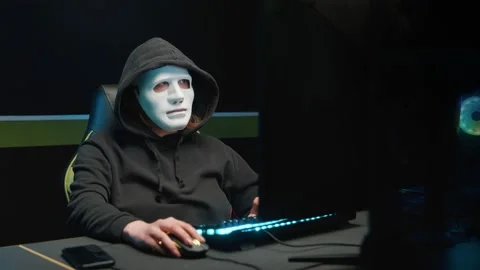 The hacker girl at the computer removes the mask from her face and looks at the 動画素材 158960219