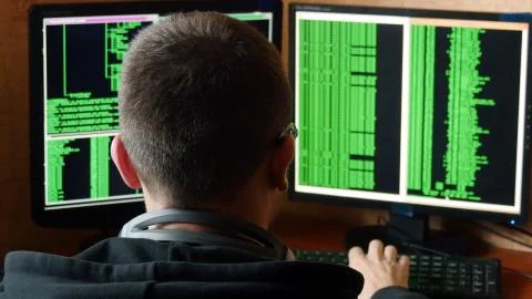 Hacker in glasses breaking code. Criminal hacker penetrating network system from Stock Photos