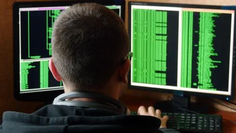 Hacker in glasses breaking code. Criminal hacker penetrating network system from Stock Photos