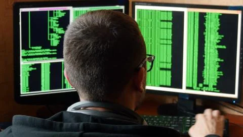 Hacker in glasses breaking code. Criminal hacker penetrating network system 스톡 사진