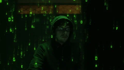 Hacker with glasses at the computer in a with the green binary code 動画素材 234929010