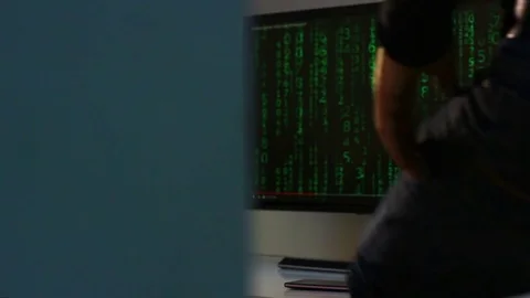 The hacker goes past the corner of the wall and sits down at the computer. Stock Footage 74714977