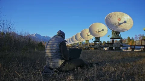 Hacker hacks the radio telescope using notebook. Man to program hacking on Stock Footage 98097955