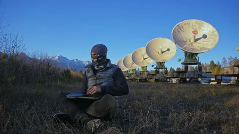 Hacker hacks the radio telescope using notebook. Man to program hacking on Stock Footage 98502694