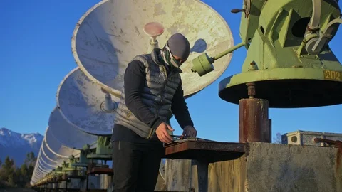 Hacker hacks the radio telescope using notebook. Man to program hacking on Stock Footage 98502729