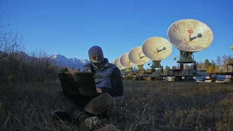 Hacker hacks the radio telescope using notebook. Man to program hacking on Stock Footage 98802649