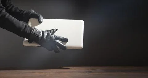 Hacker hand in a leather glove with a computer. Stock Photos