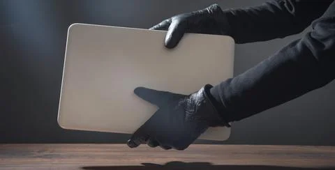 Hacker hand in a leather glove with a computer. Stock Photos