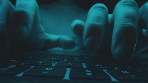 Hacker hands rapidly typing on a dark laptop keyboard illuminated by cool b.. Stock Footage 337467374