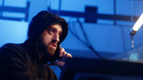 Hacker hiding in underground bunker, chatting with friend in telephone call Stock Footage 319524897