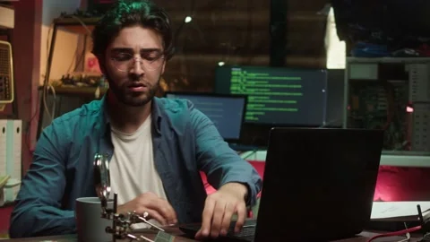 Hacker holding microchip and using laptop. Young Spanish man developing program Stock-Footage 164414537