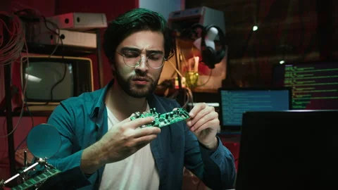 Hacker holding microchip and using laptop. Young Spanish man developing program Stock-Footage 164772304