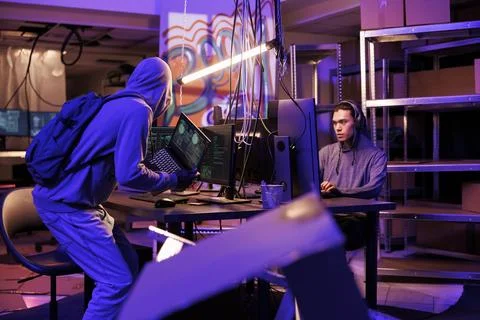 Hacker in hood bringing laptop with code 写真素材