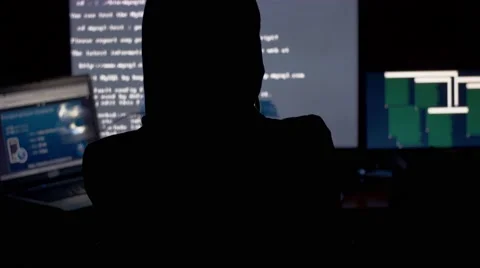 Hacker in hood cracking code using computers in dark room Video stock 68926044