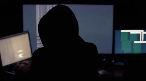 Hacker in hood cracking code using computers in dark room Stock Footage 68928477
