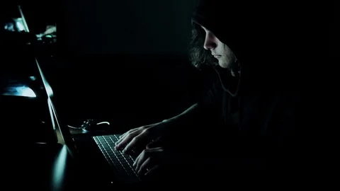 Hacker in hood cracking code using laptop  from his dark hacker room. Vídeo Stock 73810879