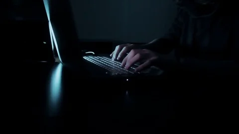 Hacker in hood cracking code using laptop  from his dark hacker room. Stock Footage 73810959