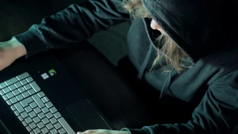 Hacker in hood cracking code using laptop  from his dark hacker room. Vídeos de archivo 73811078