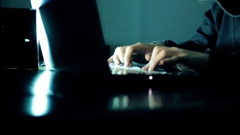 Hacker in hood cracking code using laptop  from his dark hacker room. Stock Footage 73811174