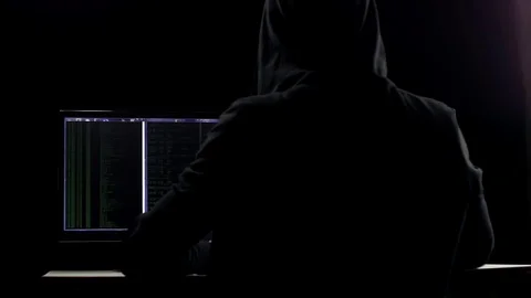 Hacker in hood cracking code using laptop and computers from his dark hacker Stock Footage 74673619
