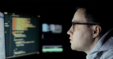 Hacker in hood cracking code using laptop and computers from his dark hacker Stock Footage 83882951