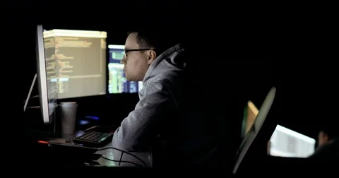 Hacker in hood cracking code using laptop and computers from his dark hacker Stock Footage 83884292
