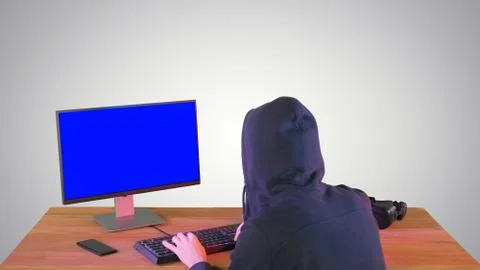 Hacker in hood cracking code using pc on gradient background. Stock Photos