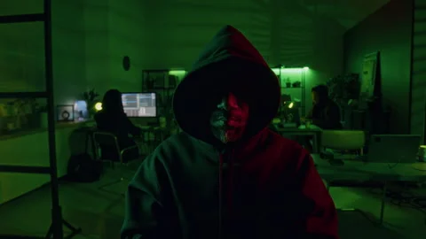 Hacker with Hood over Head and Eyes in Shadow Working in Office at Night Stock Footage 299276619