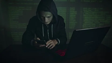 Hacker in hood typing program code while committing a cybercrime hacking Stock Footage 283996551