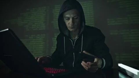 Hacker in hood typing program code while committing a cybercrime hacking Stock Footage 283996786