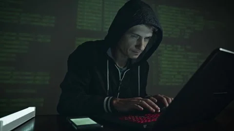 Hacker in hood typing program code while committing a cybercrime hacking Stock Footage 283996844