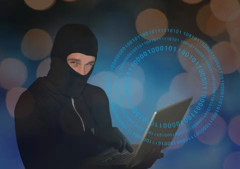 Hacker with hood using a laptop in front of digital background 写真素材