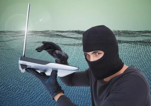 Hacker with hood using a laptop in front of digital number field Foto stock