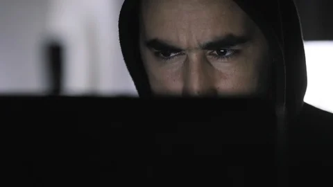 Hacker in hood working on a computer at dark room at home Stock Footage 112228786