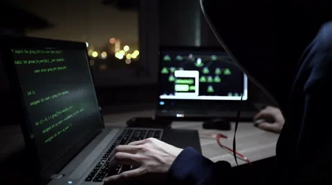 Hacker in hooded jacket using computer at table Stock Footage 60606112