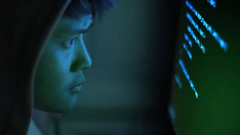 Hacker in Hoodie Coding at Computer Screen in Dark Blue Cybersecurity Setting Stock Footage 336052985