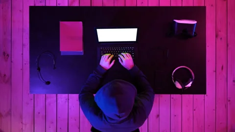 Hacker in hoodie typing code in program using laptop in dark studio. White Video stock 101826860
