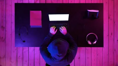 Hacker in hoodie typing code in program using laptop in dark studio. White 스톡 사진