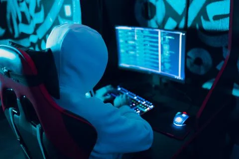 Hacker in hoodie working hacks code site on personal computer with green light Stock Photos