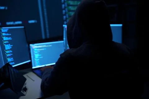Hacker in Hoodie Working at Multiple Computer Monitors 写真素材