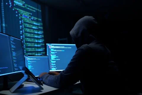 Hacker in Hoodie Working on Multiple Monitors at Night 写真素材